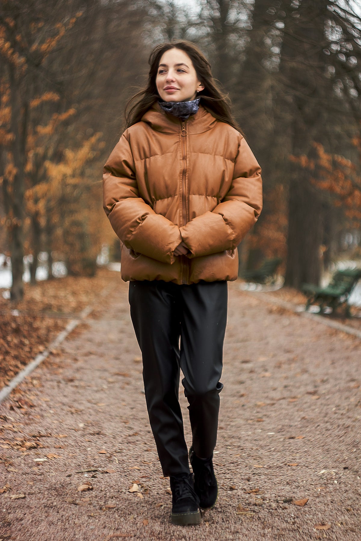 woman in brown leather jacket and black pants standing on road during daytime